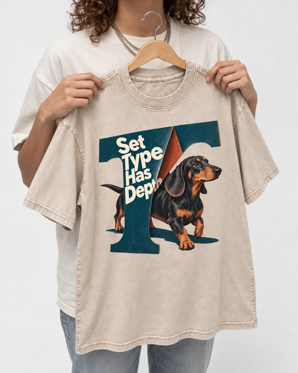 Dachshund Set Type Has Depth Folded Letter Graphic Washed Tee in Apricot, held up on a hanger
