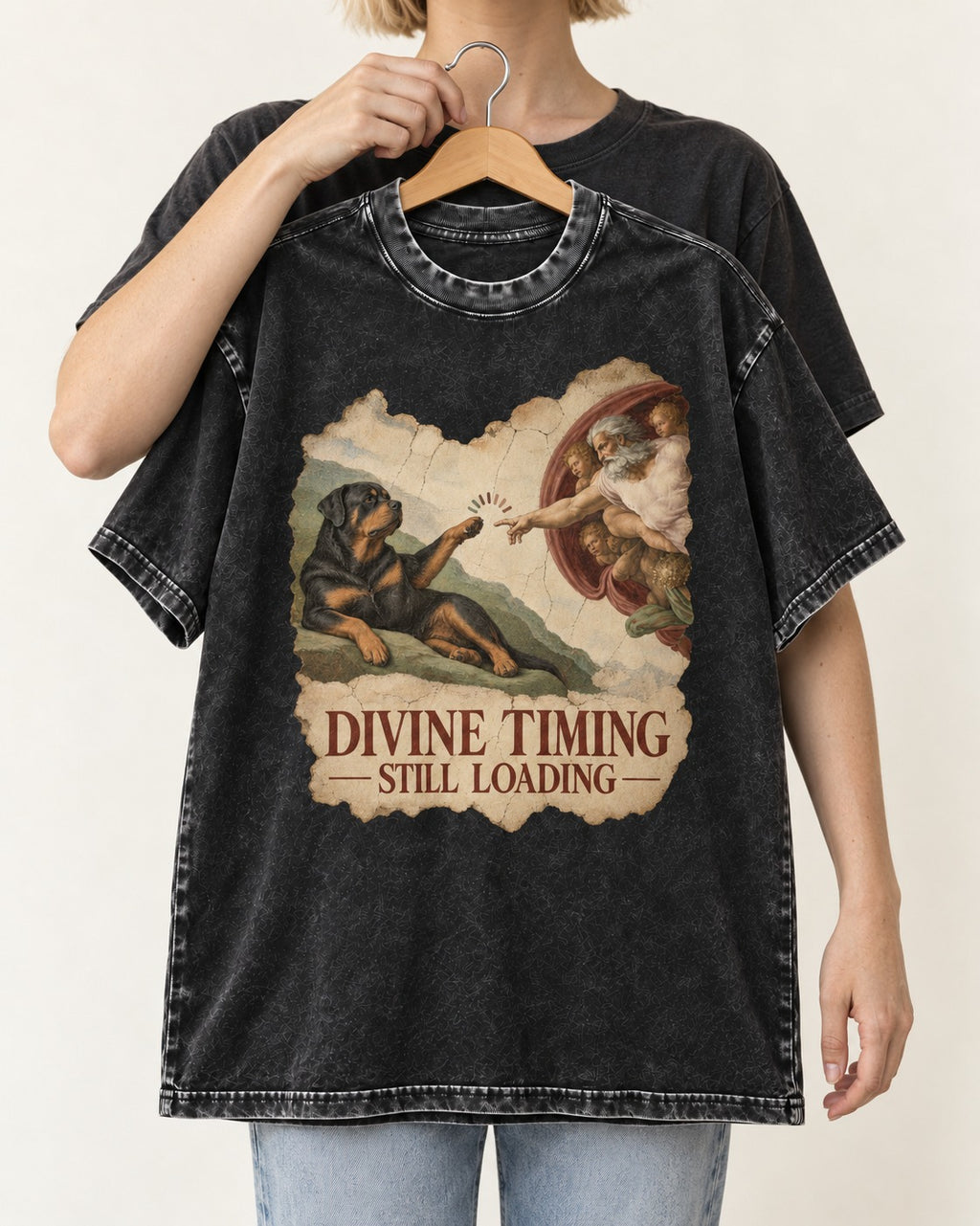 Rottweiler Divine Timing Still Loading Creation Parody Graphic Washed Tee in Black, held up on a hanger