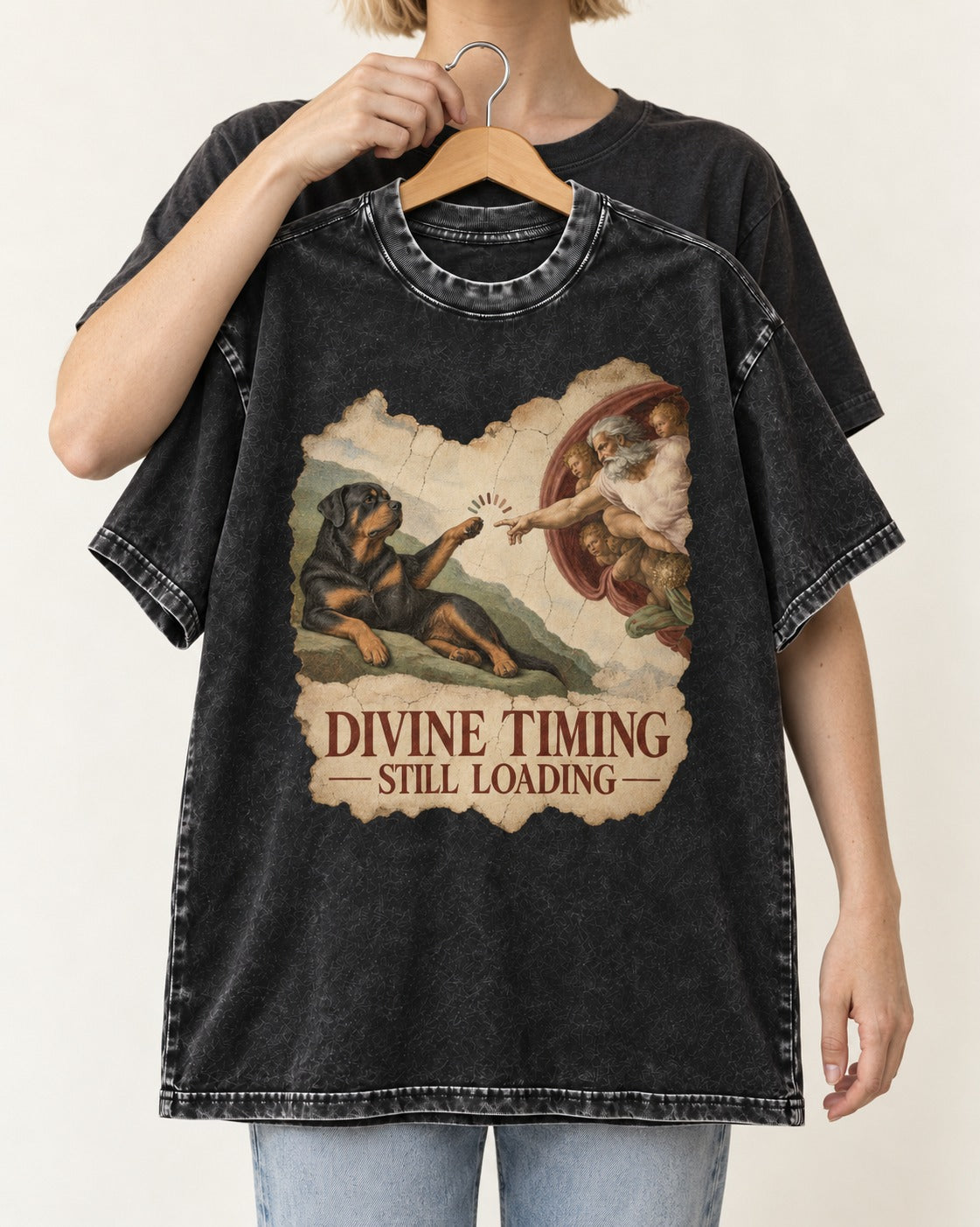 Rottweiler Divine Timing Still Loading Creation Parody Graphic Washed Tee in Black, held up on a hanger