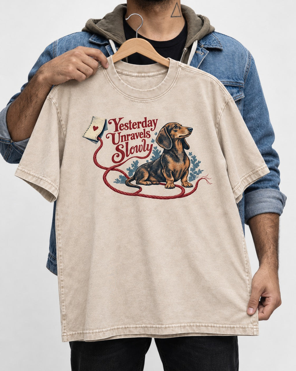 Yesterday Unravels Slowly with Dachshund Washed Tee in Apricot, held up on a hanger