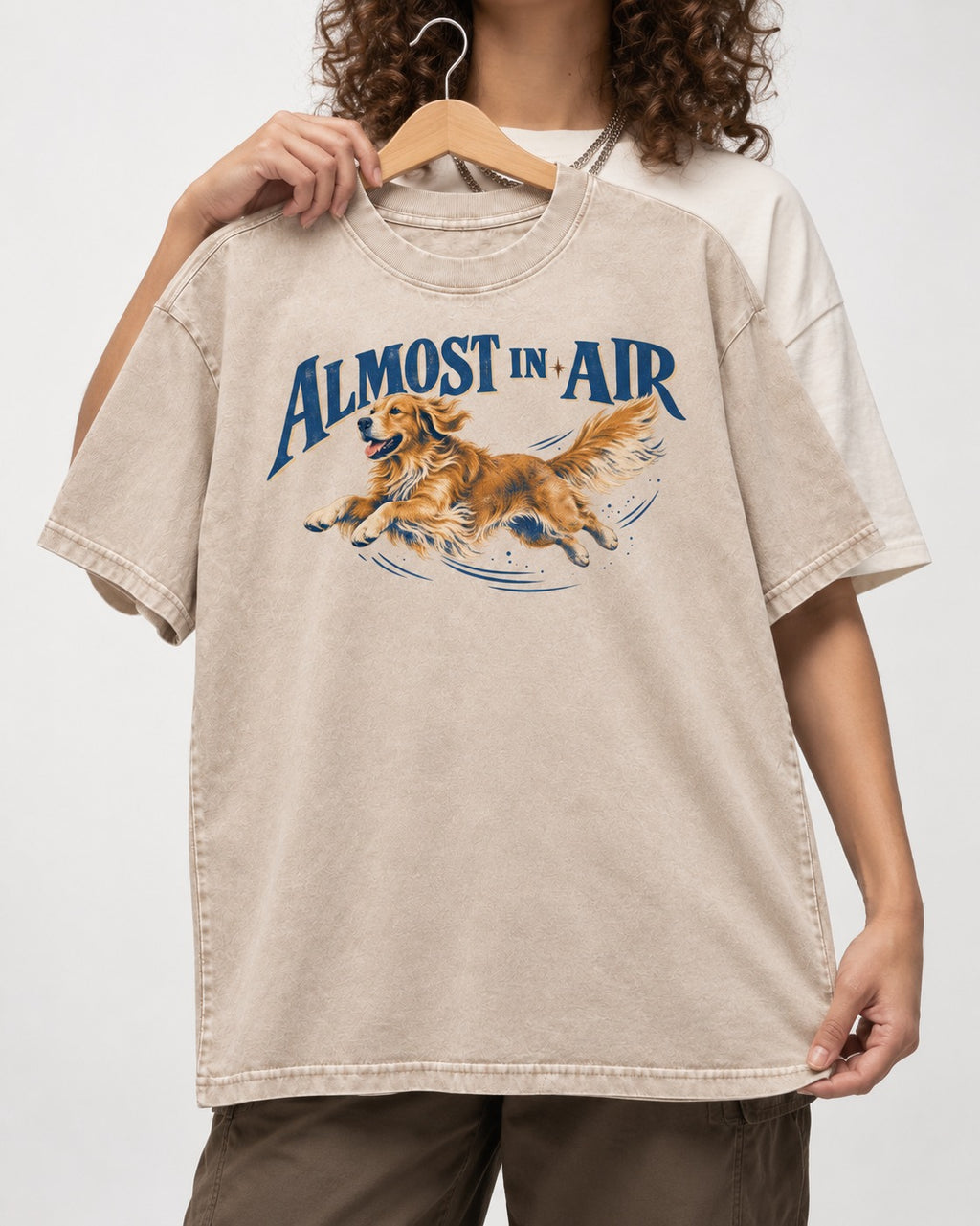 Golden Retriever Almost in Air Flying Graphic Washed Tee in Apricot, held up on a hanger