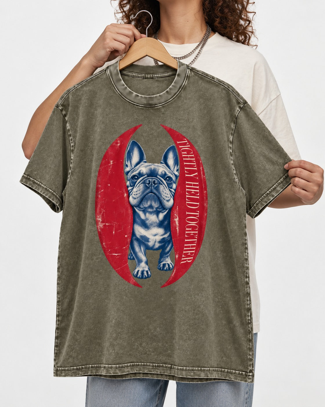 Frenchie Tightly Held Together Red Oval Graphic Washed Tee in Army Green, held up on a hanger