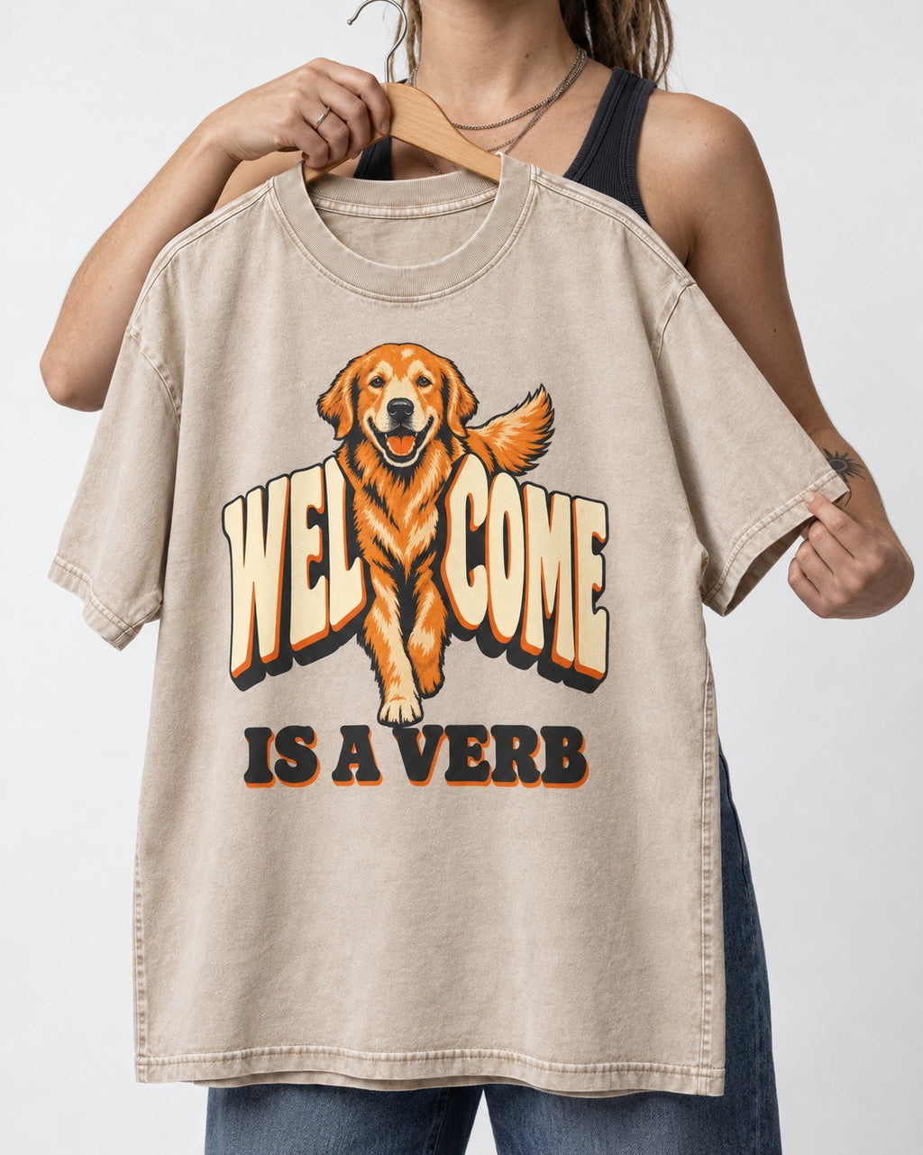 Golden Retriever Welcome Is a Verb Washed Tee in Apricot, held up on a hanger