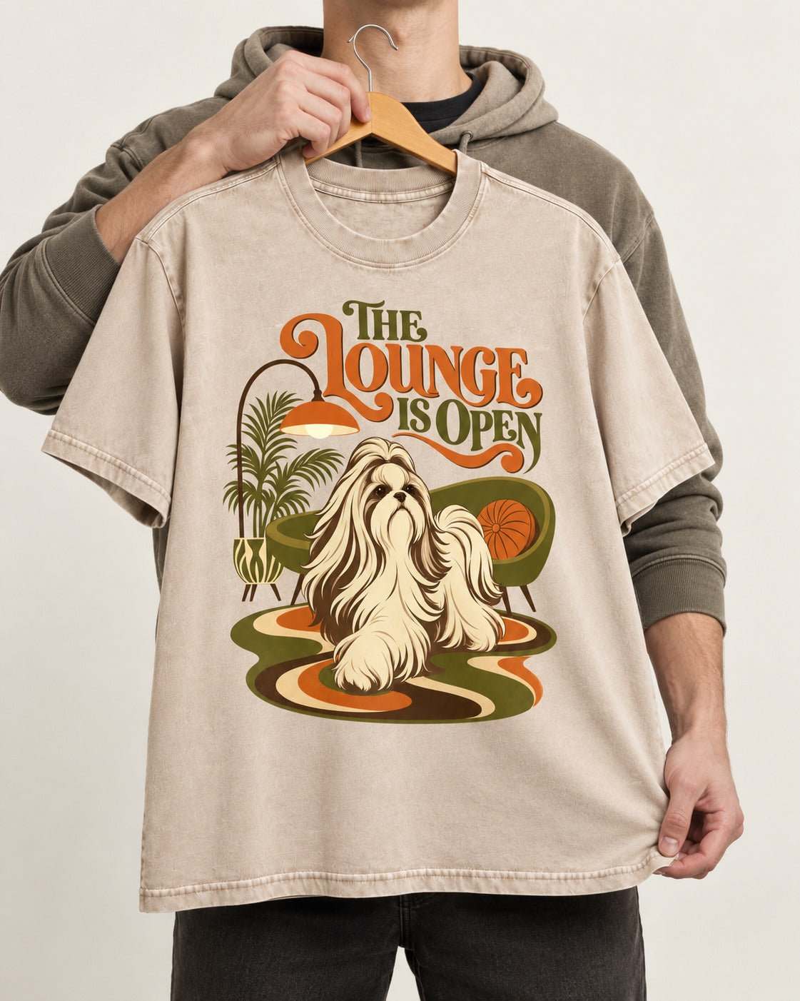 The Shih Tzu Lounge Is Open Washed Tee in Apricot, held up on a hanger