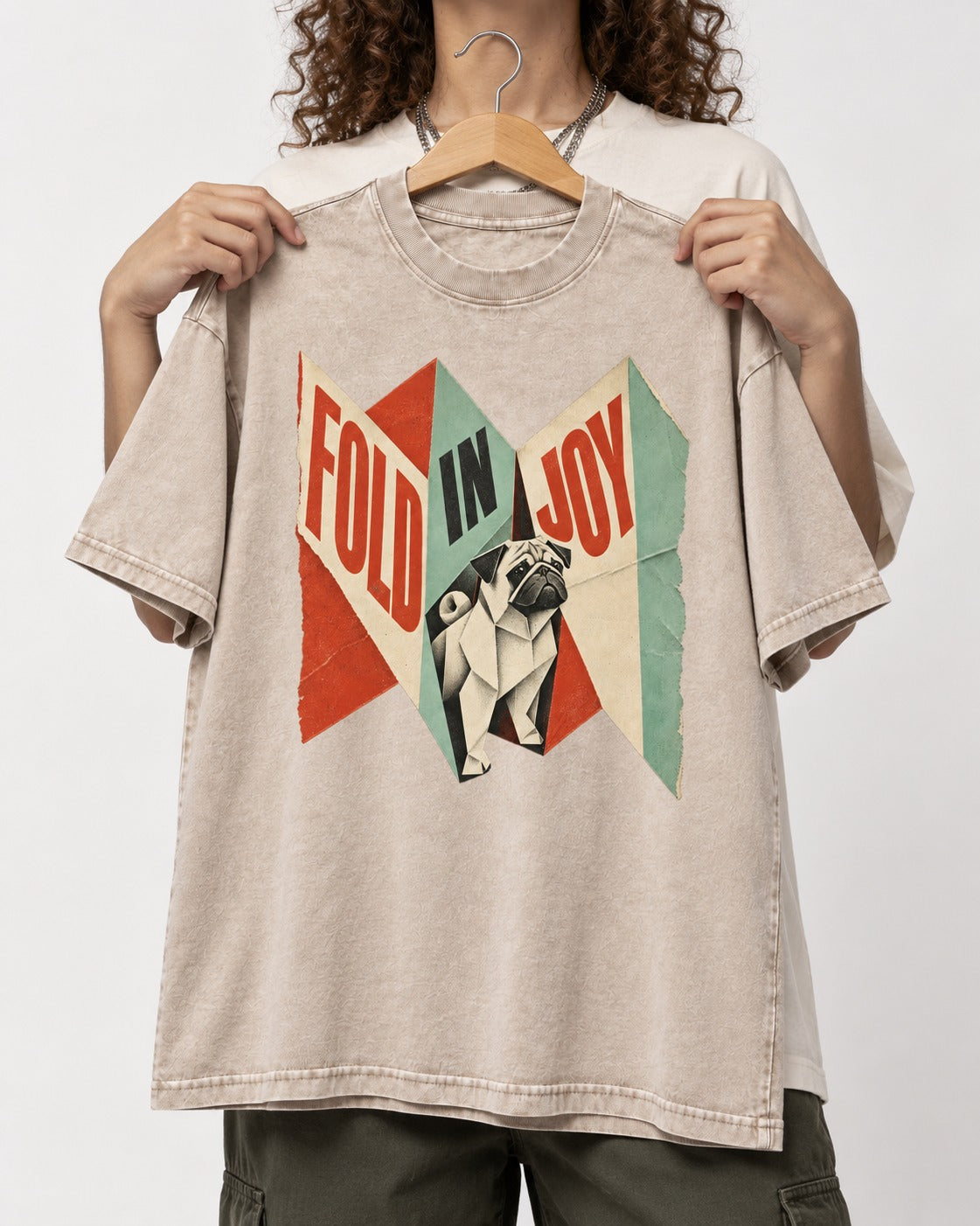 Pug Fold in Joy Geometric Poster Graphic Washed Tee in Apricot, held up on a hanger