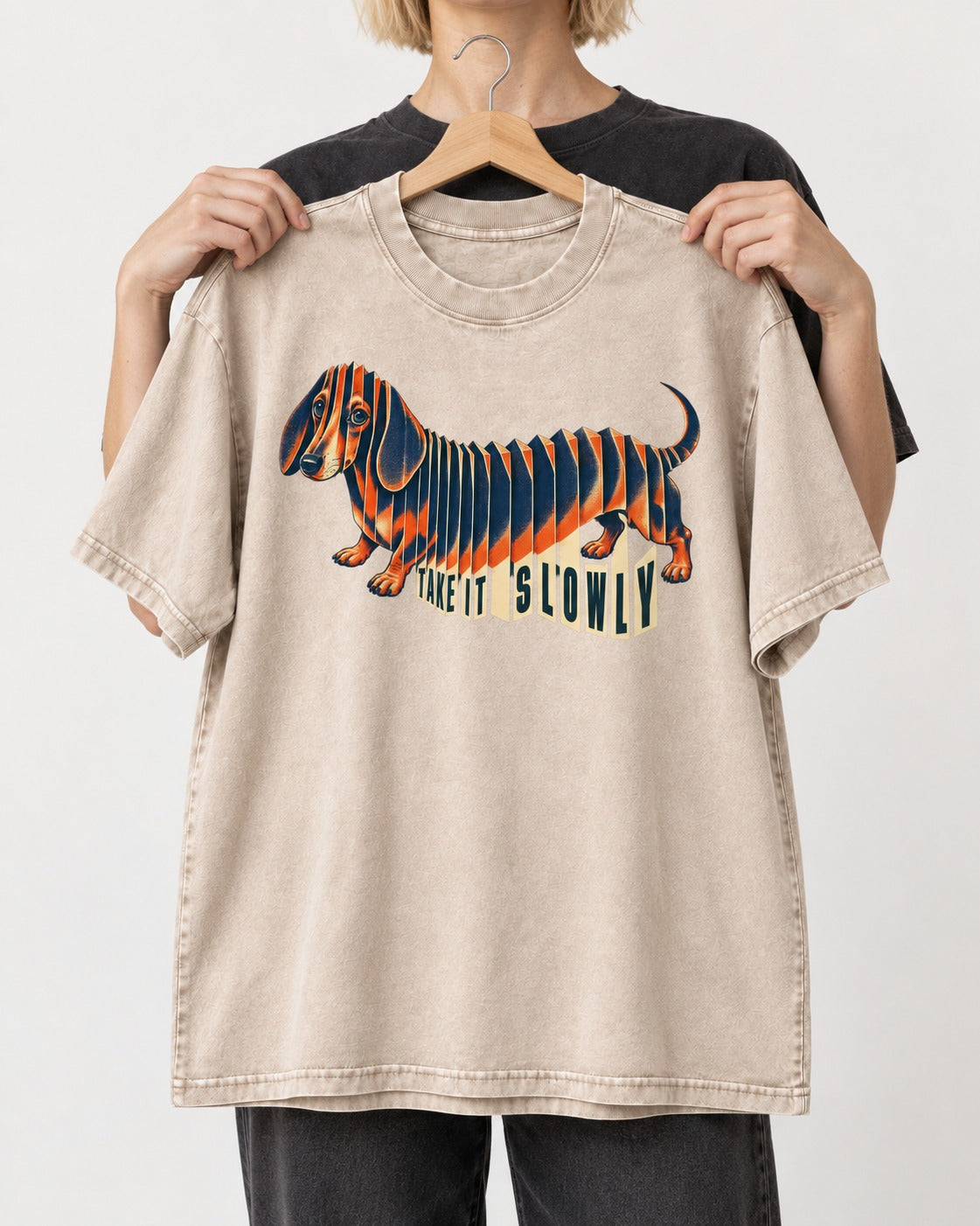 Take It Slowly Dachshund Washed Tee in Apricot, held up on a hanger